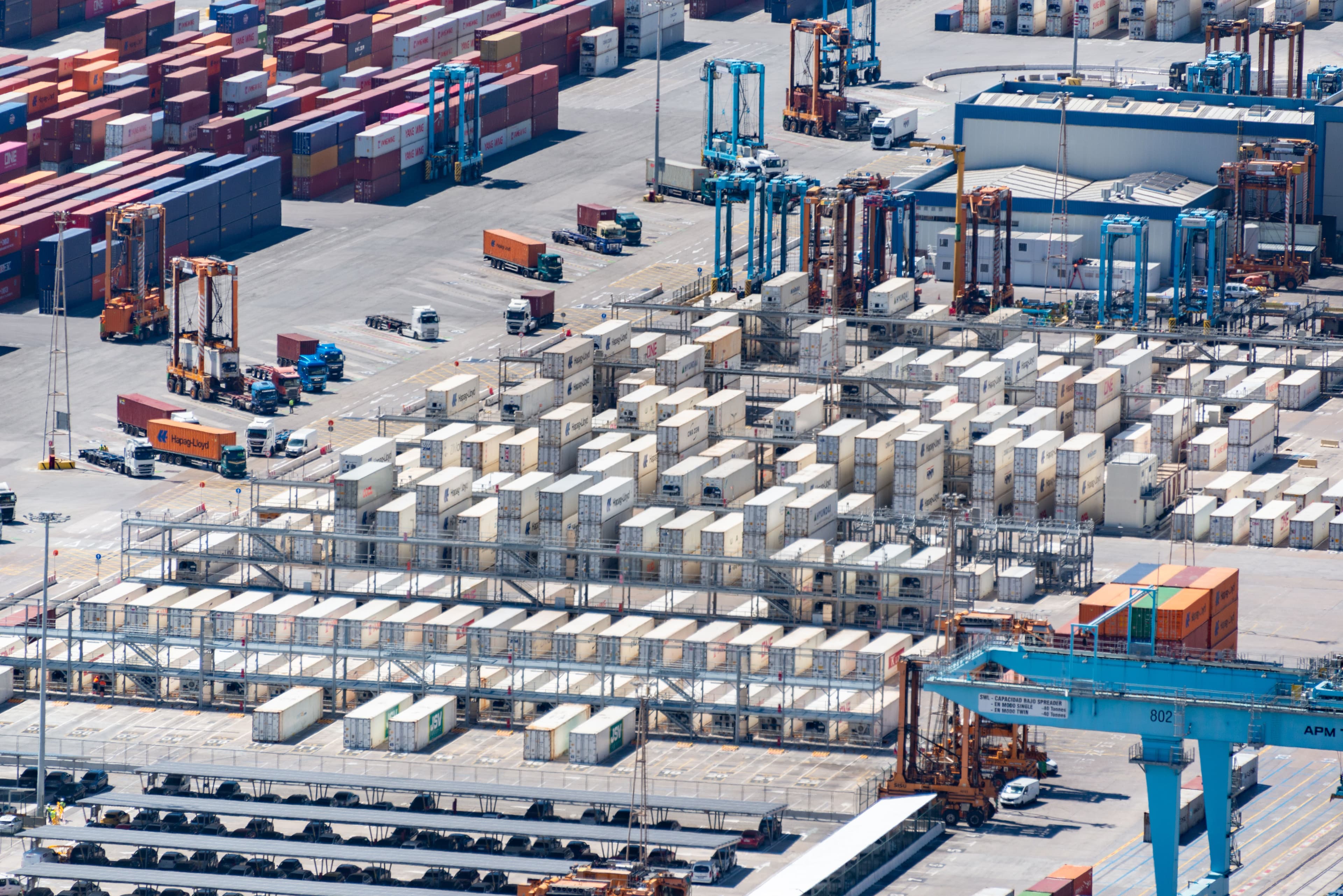 Stacked shipping containers lit at a port terminal at dusk.